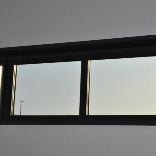 Fast svart aluminiumfönster sett från insidan mot blå himmel